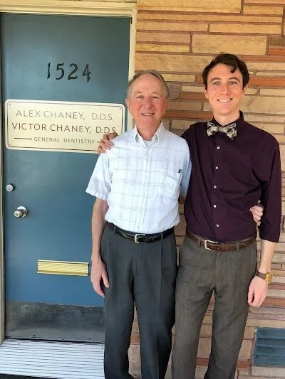 A photograph of the two dentists standing outside the practice door, beside a plaque reading Alex Chaney DDS, Victor Chaney DDS, General Dentistry.